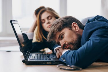 İşadamı ve kadın laptopun önünde büroda çalışıyor.