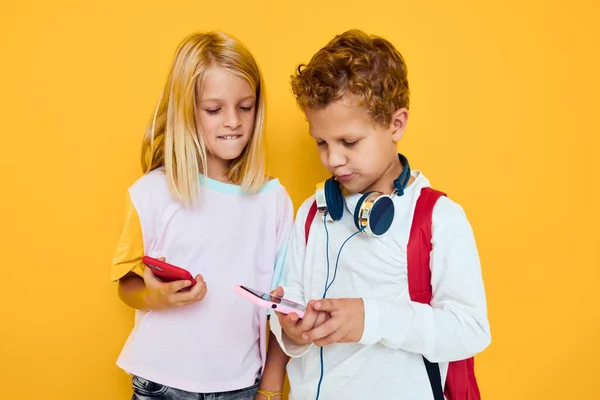 Foto von zwei kleinen Kindern Mädchen mit Blick auf das Telefon Unterhaltung Kommunikation gelben Hintergrund — Stockfoto