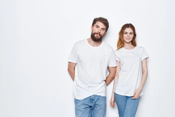 Veselý muž a žena v bílých trička a džíny design studio světlo pozadí — Stock fotografie