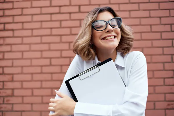 Žena v obleku cihlová zeď složka pro papíry profesionální světlo pozadí — Stock fotografie