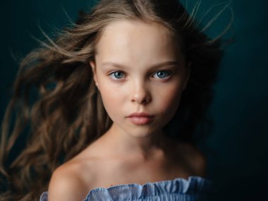 Kıvırcık saçlı kız makyaj stüdyosunda poz veriyor.