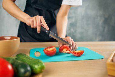 Mutfaktaki aşçı kadın izole edilmiş sebzeleri kesiyor.