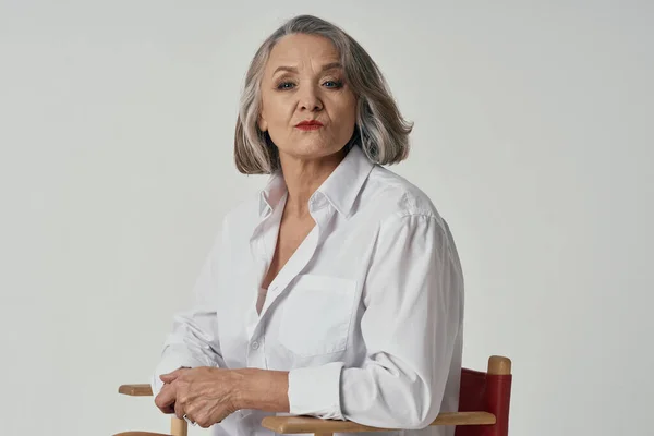 Starší žena stojí v blízkosti židle životní styl bílá košile pózování — Stock fotografie