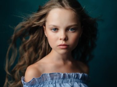 Kıvırcık saçlı kız makyaj stüdyosunda poz veriyor.