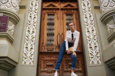 Elinde kitapla dışarıda eğitim okuyan bir öğrenci.