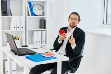 Takım elbiseli bir adam, bir dizüstü bilgisayarın önünde ofiste çalışıyor.