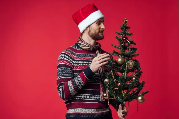 Noel Baba şapkalı neşeli adam Noel süsleri Noel stüdyosunda poz veriyor. — Stok fotoğraf