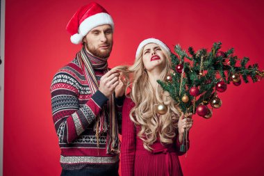 Elinde Noel ağacı olan bir adam bir kadının yanında duygu yüklü bir bayram süsü taşıyor.