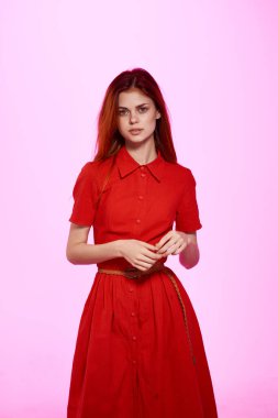 Kırmızı elbiseli güzel bir kadın. El hareketi. Pembe arka plan.