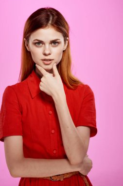 Kırmızı elbiseli güzel bir kadın. El hareketi. Pembe arka plan.