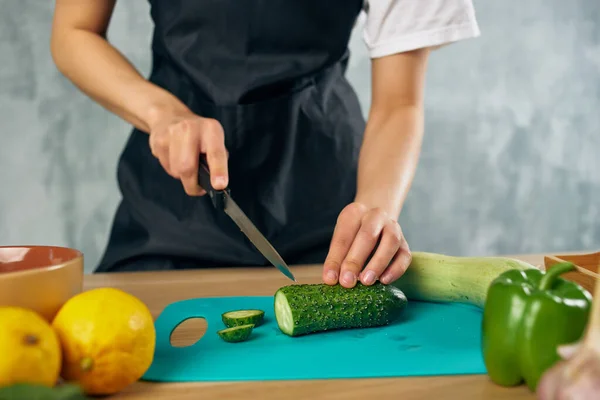 Donna in grembiule nero Cucinare sano mangiare tagliere — Foto Stock