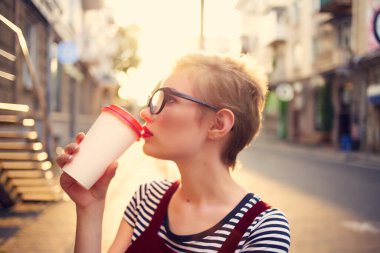 Kısa saçlı kadın bardakta içki içer yaz yürüyüşü yapar.