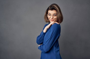 Mavi gömlekli kadın zarif gözlüklü poz veriyor.