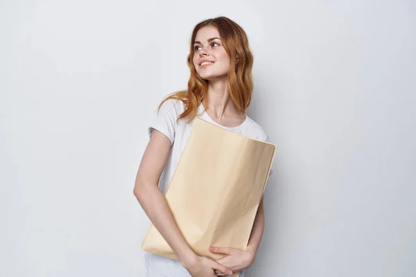 Жінка в білій футболці з пакетом в руках покупки — стокове фото