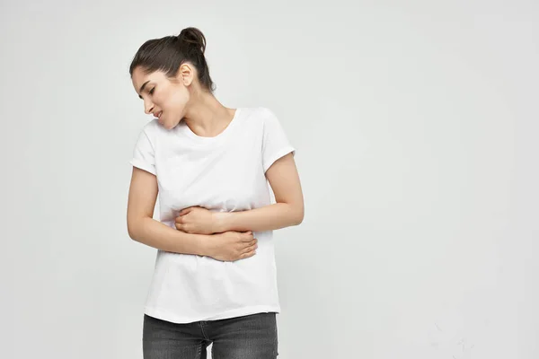 Woman in white t-shirt holding her stomach diarrhea pain health problems — Stock Photo, Image
