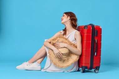 Kırmızı şapkalı ve mavi arka planda bavulu olan kadın. Yüksek kalite fotoğraf