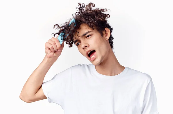 Um cara em um branco t-shirt pentes cabelo encaracolado — Fotografia de Stock