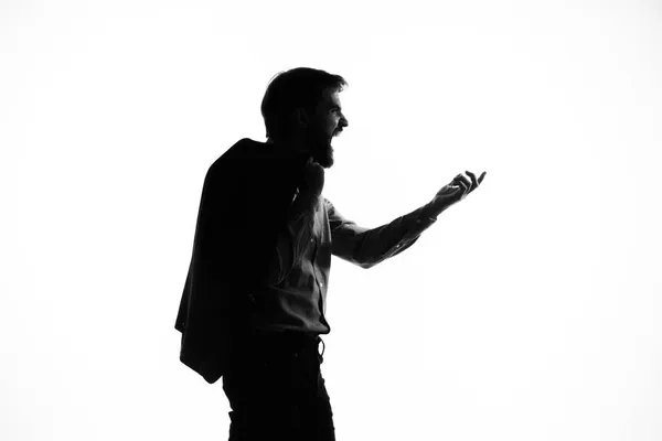 O homem em uma arma de terno nas mãos das emoções silhueta luz fundo — Fotografia de Stock