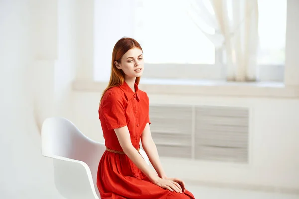 빨간 드레스를 입은 의자에 앉아 있는 여자 — 스톡 사진