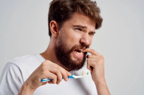 Spazzolino da denti uomo barbuto in mano igiene denti puliti sfondo chiaro — Foto Stock