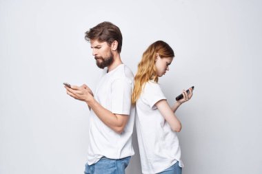 Beyaz tişörtlü, ellerinde telefonlar olan genç bir çift.