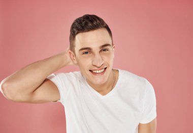 Beyaz tişörtlü yakışıklı, pembe arka planlı eğlenceli adam.
