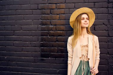 Güzel bir kadın dışarıda yürüyor. Yazın siyah tuğlalı bir duvar.