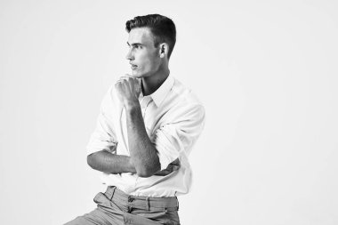 Sandalyeye oturmuş yakışıklı bir adam şık moda hafif arka planda oturuyor.