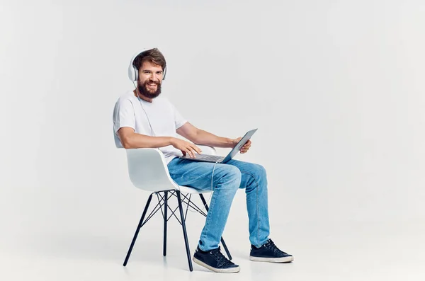 Jeune homme assis sur une chaise avec un ordinateur portable dans le divertissement casque — Photo