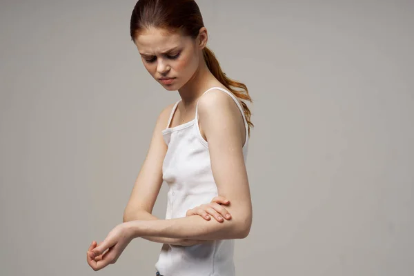 Γυναίκα σε λευκό t-shirt εκμετάλλευση για τα προβλήματα υγείας του αγκώνα θεραπεία αρθρώσεων στούντιο — Φωτογραφία Αρχείου
