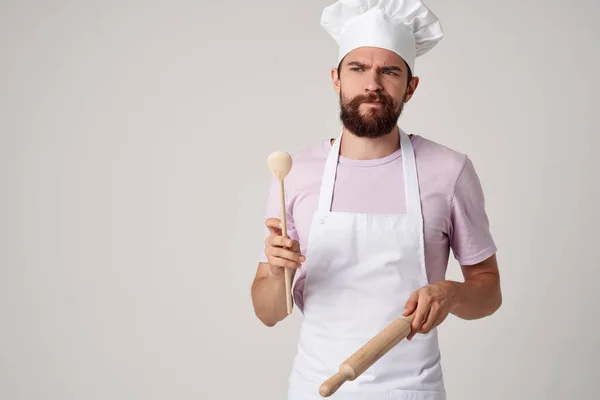Cuoco professionista in uniforme con un cucchiaio in mano lavorare su sfondo chiaro — Foto Stock