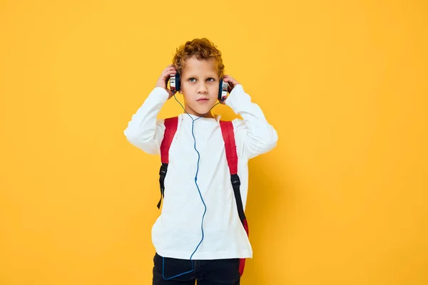Skolpojke med hörlurar musik Röd ryggsäck gul bakgrund — Stockfoto