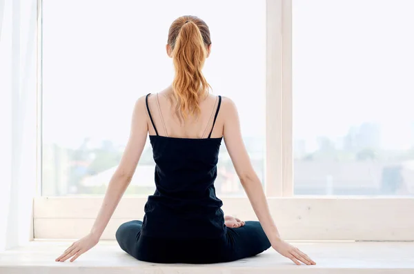 Mujer sentada en posición de loto ejercicio meditación yoga cerca de ventana — Foto de Stock