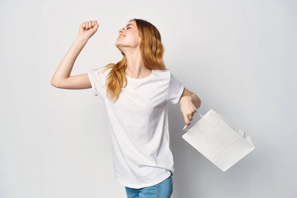 Женщина в белой футболке с пакетом в руках подарок — стоковое фото