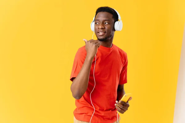 Homem alegre de aparência africana em fones de ouvido música fundo amarelo — Fotografia de Stock