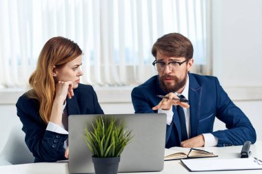 İş arkadaşları ofiste bir dizüstü bilgisayarın önünde sohbet ediyorlar.