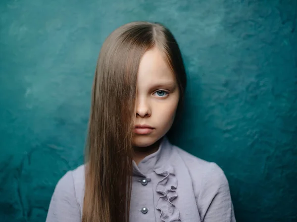 Dívka s dlouhými vlasy v šatech pózovat zelené pozadí smutný vzhled — Stock fotografie