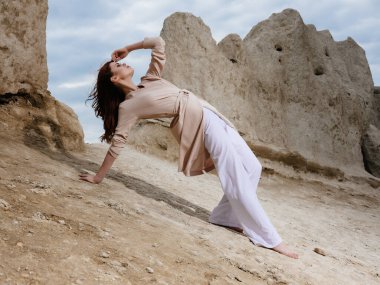 Kadın kumda zarif bir şekilde oturuyor.