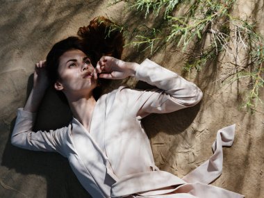 Ceketli çekici kadın yaz mevsiminde kumların üzerinde uzanır.