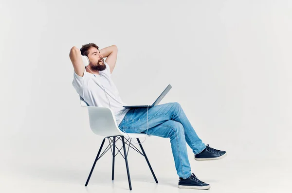 Brodaty mężczyzna siedzi na krześle z laptopem w słuchawkach rozrywki — Zdjęcie stockowe