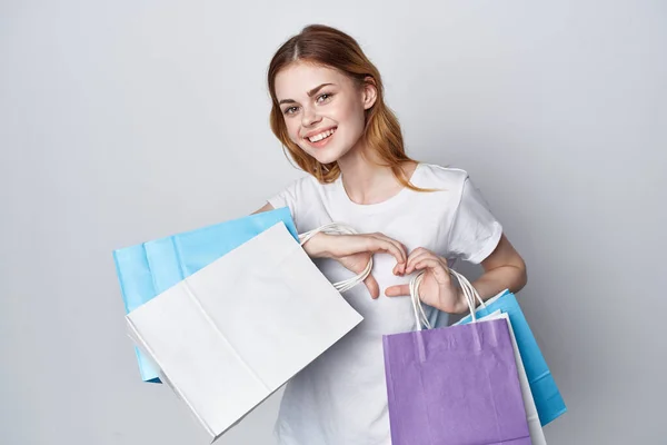 Mujer alegre en una camiseta blanca compras bolsas multicolores Shopaholic —  Fotos de Stock