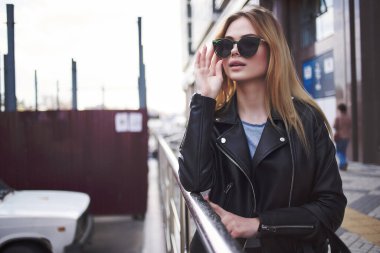 Güneş gözlüklü tatlı sarışın dışarıda yürüyor.