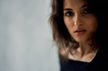 Siyah elbiseli esmer pencere kenarında poz veriyor.