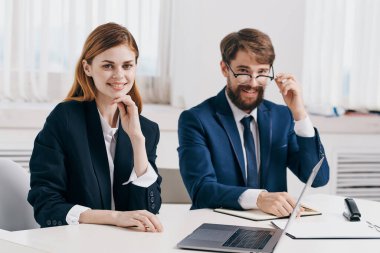 Erkek ve kadın yöneticiler dizüstü bilgisayar profesyonelleri teknolojisinin önünde masada oturuyorlar.