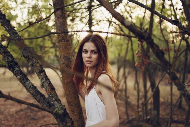 Beyaz elbiseli kadın yaz ormanlarında yürüyor.