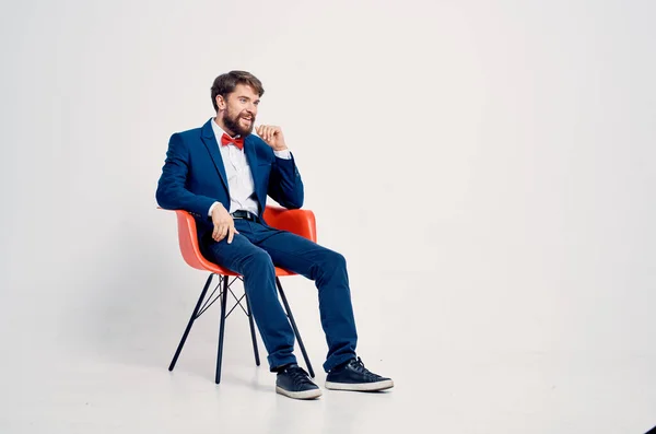 Homme d'affaires joyeux dans un costume assis sur une chaise rouge posant — Photo