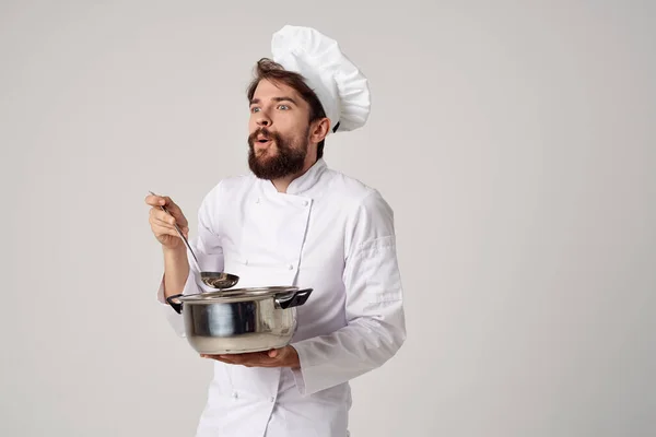 Um homem com roupas de chefs segurando uma panela em suas mãos cozinha trabalho cozinhar — Fotografia de Stock