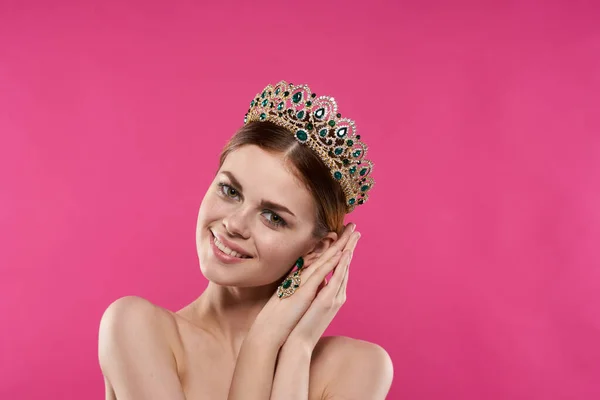 beautiful woman with a crown on her head makeup decoration pink background