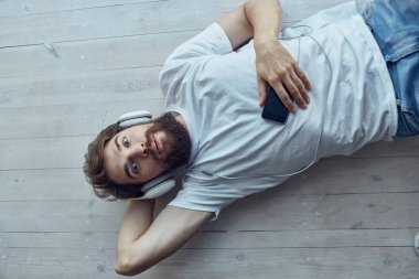 Beyaz tişörtlü adam pencerede uzanıyor kulaklık takıyor yaşam tarzı