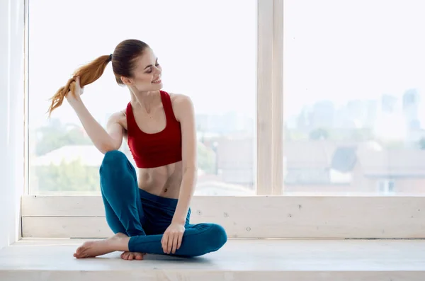 Sportowa kobieta robi ćwiczenia jogi w pobliżu okna — Zdjęcie stockowe